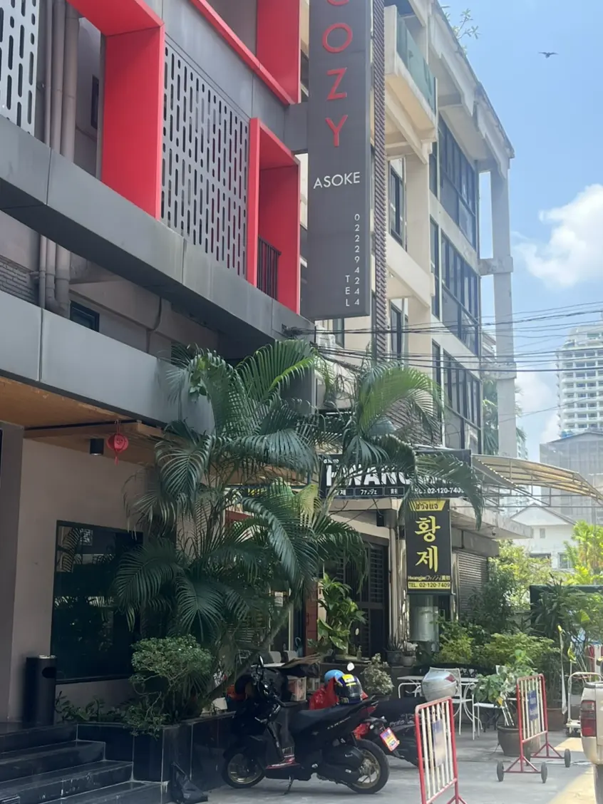 한국인 여행자가 스마트폰의 호텔 예약 앱과 노트북의 가격 비교 화면을 함께 띄워놓은 플랫레이 컷